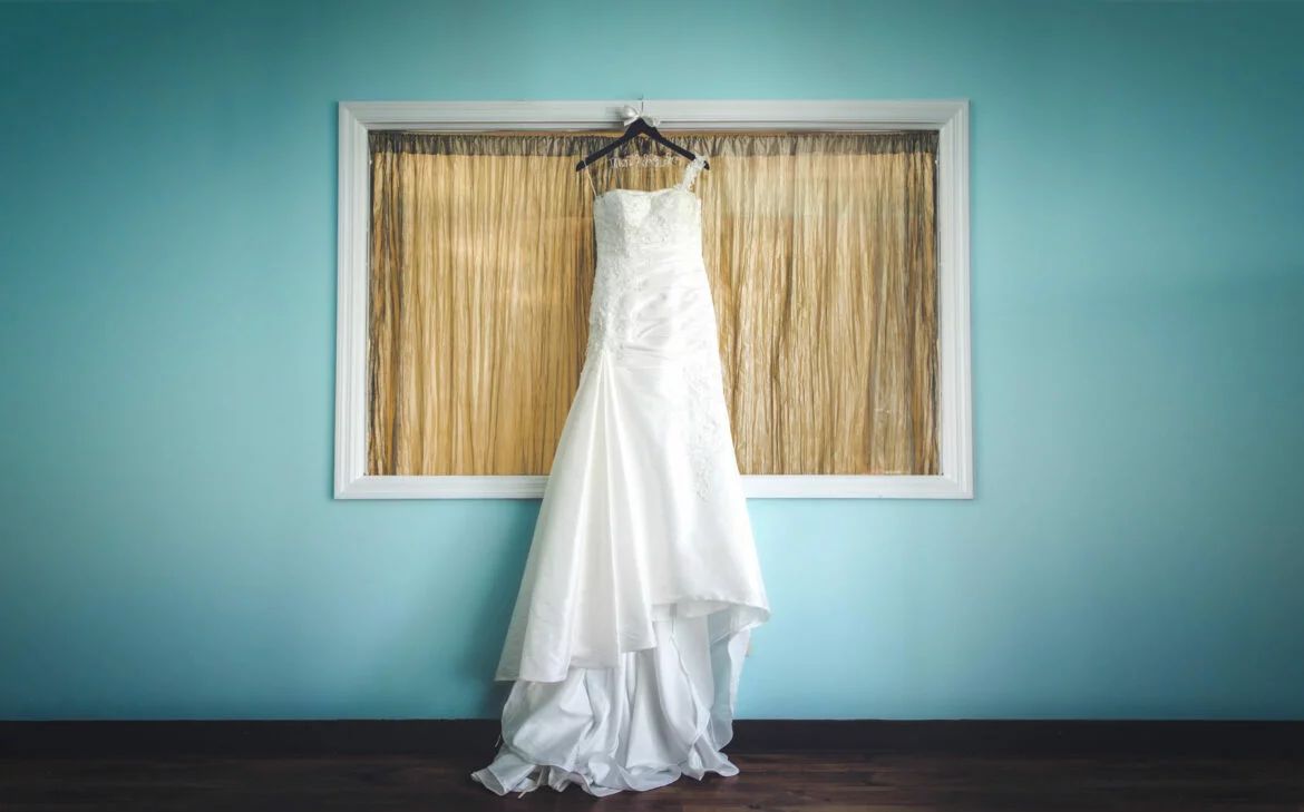 Wedding dress on a hanger in front of a window