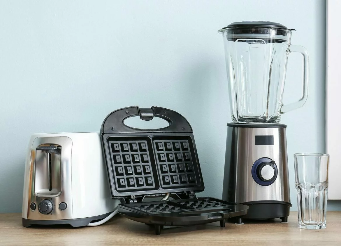 Kitchen appliances including a toaster, waffle maker and blender on a counter