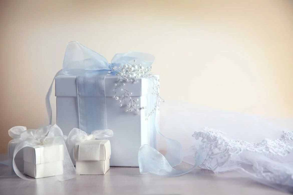 Three wedding registry gifts wrapped with tulle ribbon next to a veil
