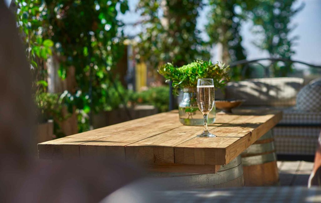 A rustic wood table with a glass of sparkling wine in a vineyard in Sonoma Valley