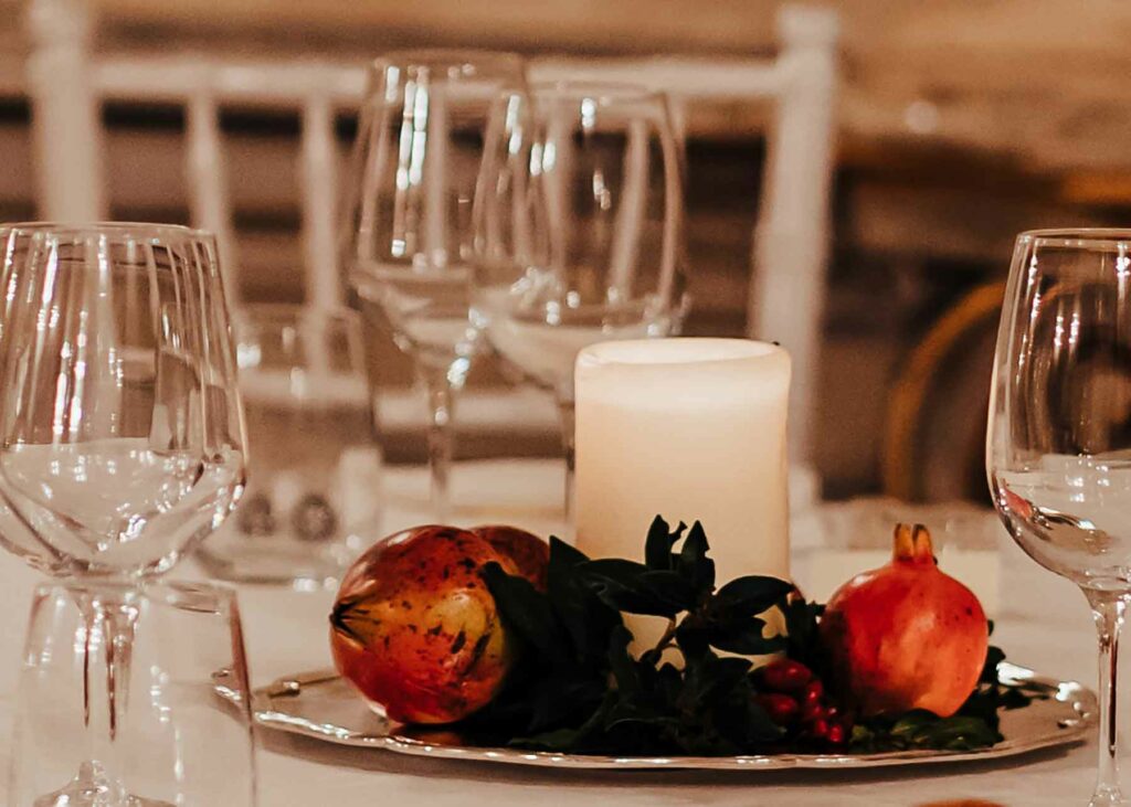 Pomegranates sit atop a shining metal tray in a sophisticated fall centerpiece with a white candle