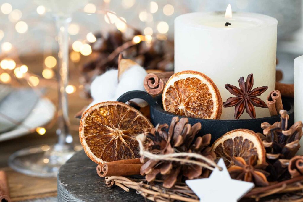 Fall wedding centerpiece with dried orange slices, cinnamon sticks, a wreath of branches and a white candle