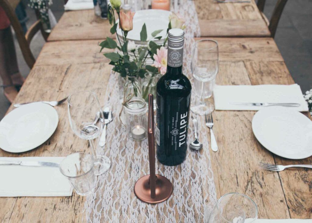 A lace table runner sits atop a wooden table at a wedding venue to create rustic elegance