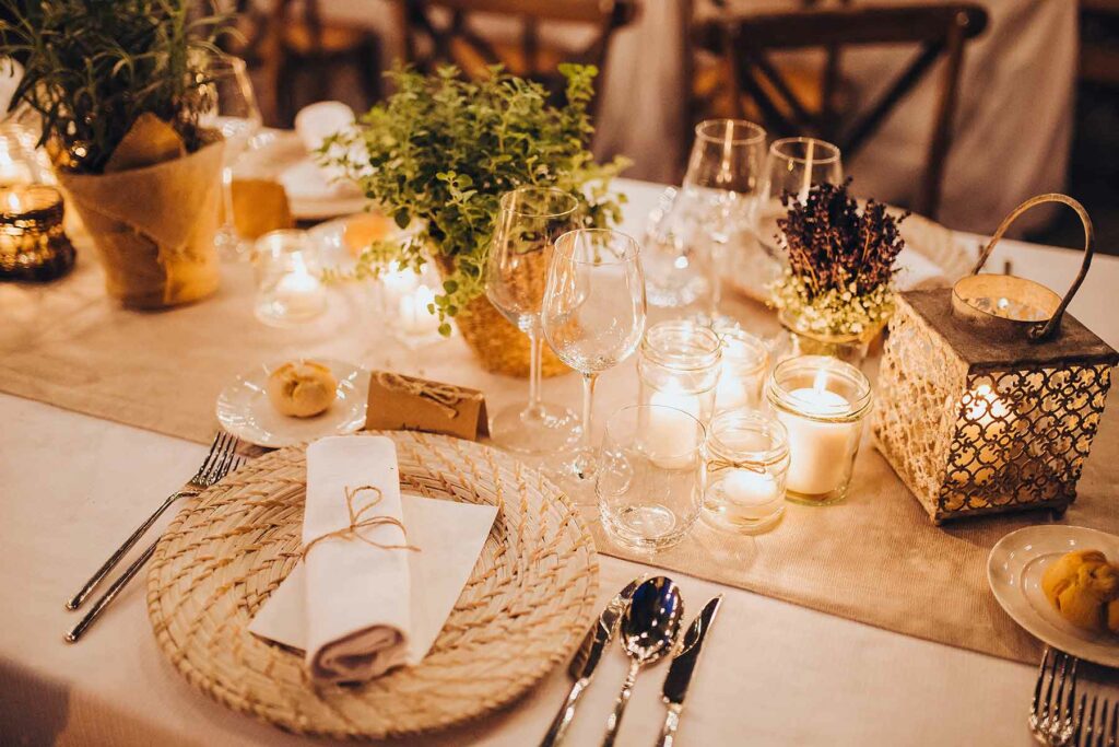 A woven placemat is an eye-catching choice next to a collection of seasonal greenery, votive candles and a gold lantern