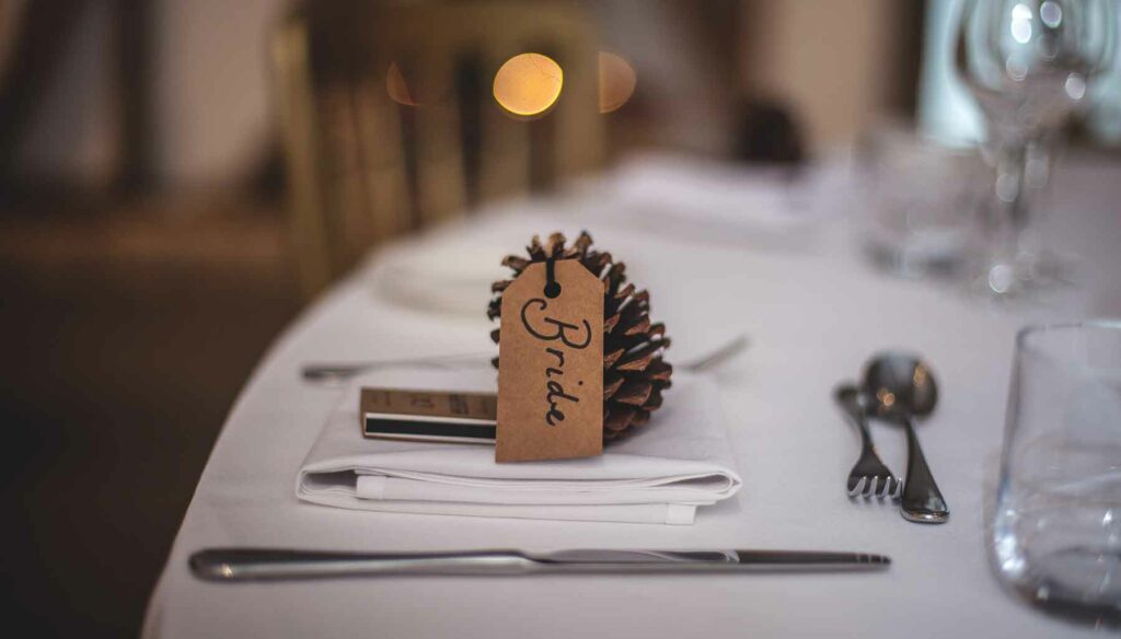 Pinecone decor with a name card that reads "bride" at a fall wedding reception