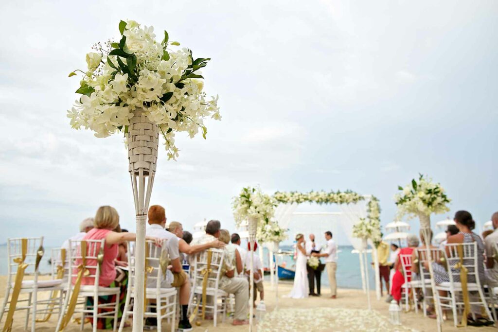 Beach wedding ceremony with seated guests watching the couple exchange vows