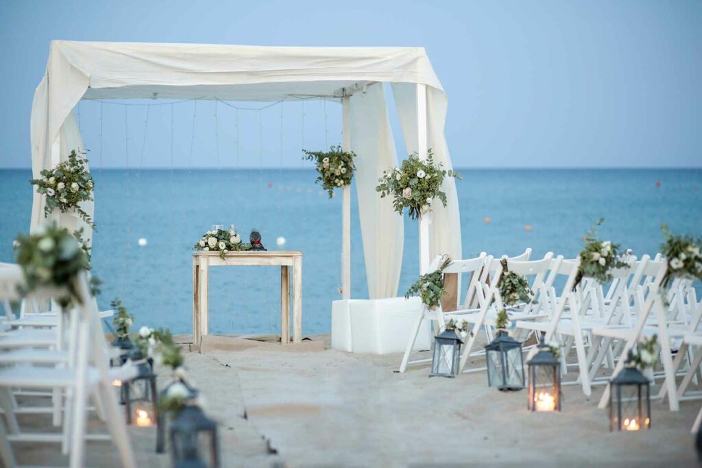 A beach wedding ceremony venue with chairs, an officiant's table and canopy overlooking the ocean