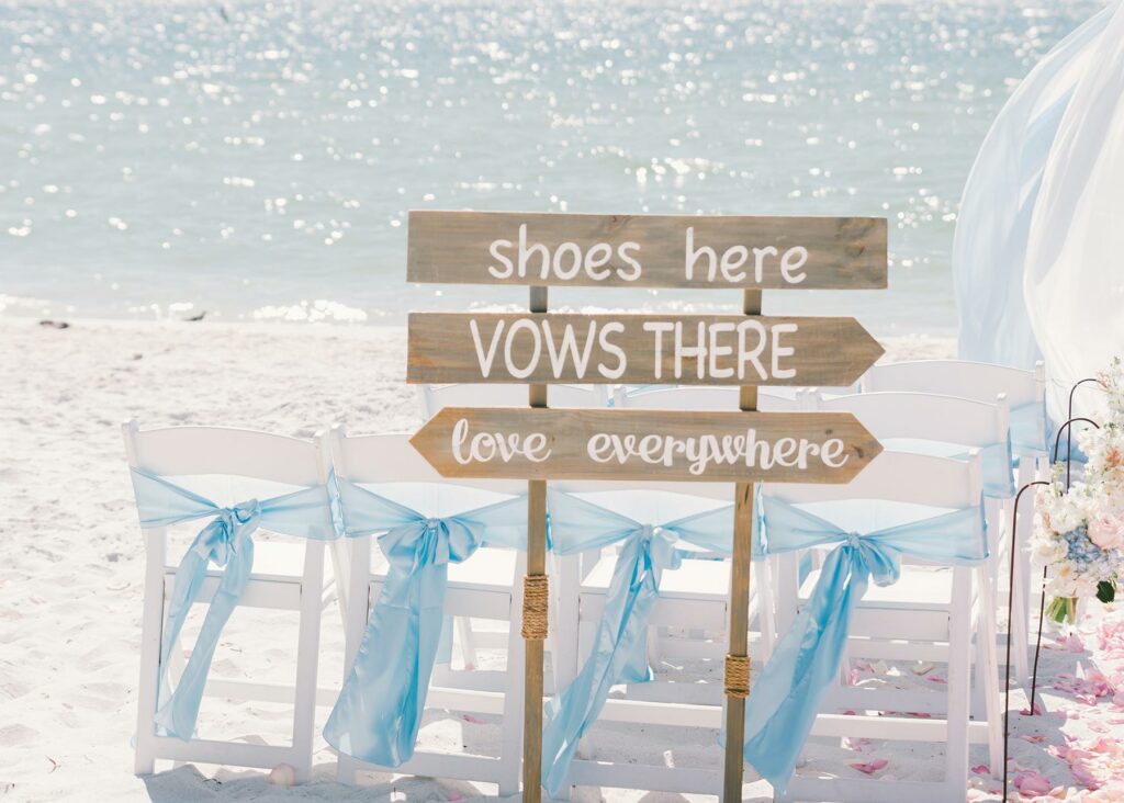 A sign at a beach wedding directing guests to shoes for the sand