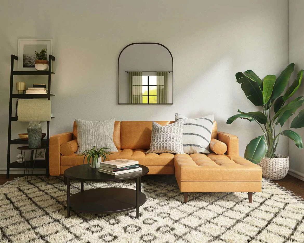 A living room features statement furniture including a large couch with a chaise lounge, a leaning bookshelf and a coffee table