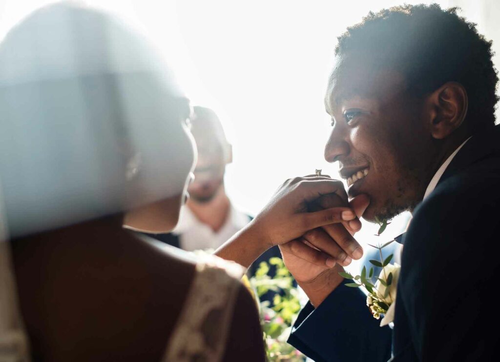A close-up of a groom about to kiss a bride's outstretched hand