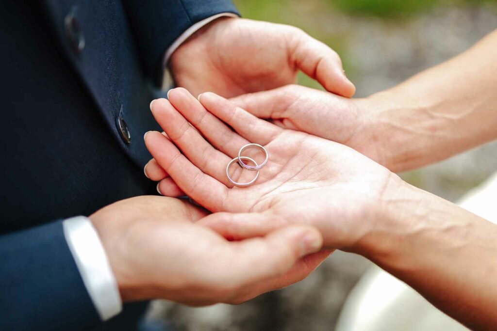 A close-up of a couple's hands holding wedding rings in their palms