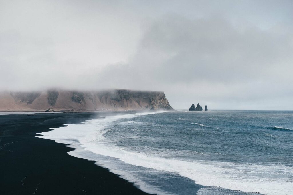 The shoreline of a black sand beach near the village of Vik in Iceland