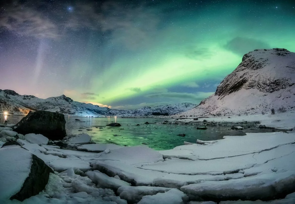 Northern lights shine brightly over snow-capped mountains during a honeymoon in Iceland