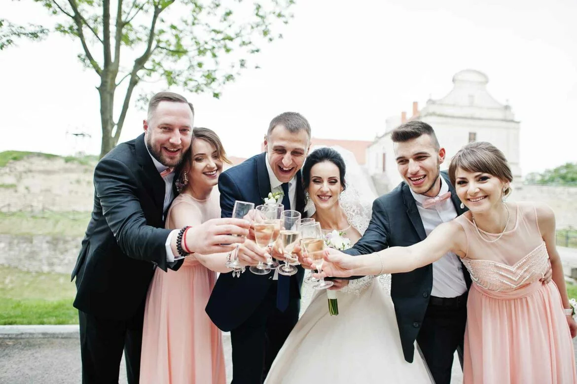 Wedding party surrounding a couple clinking glasses