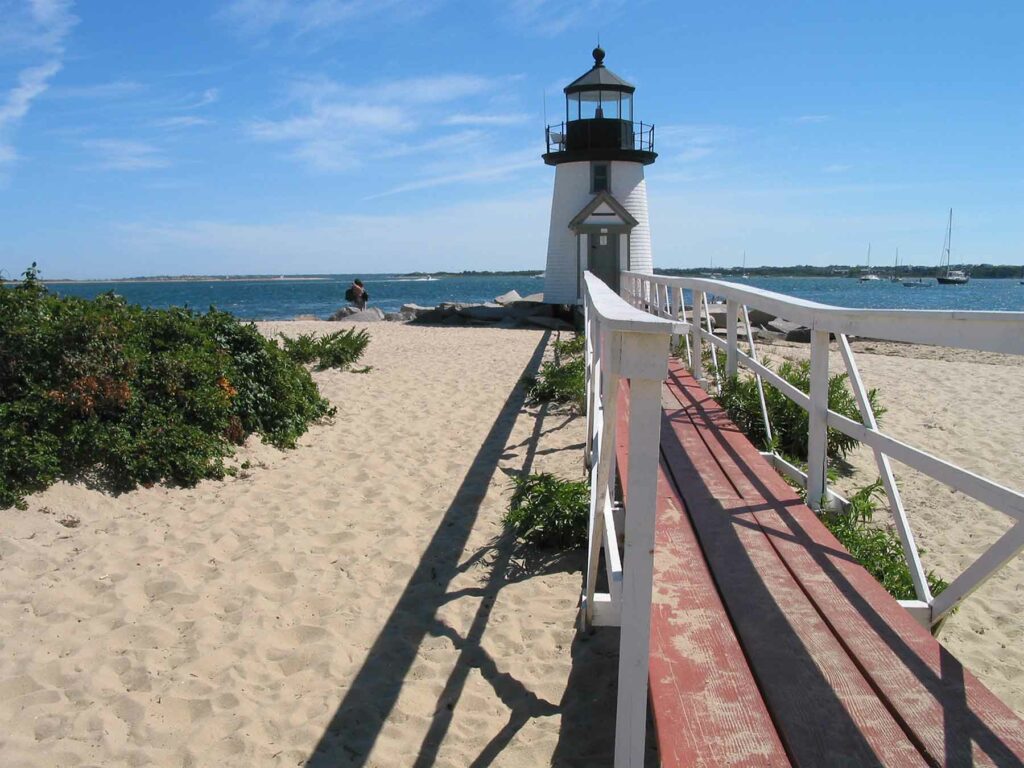 A narrow bridge leading to a black and white lighthouse in Nantucket, Massachusetts