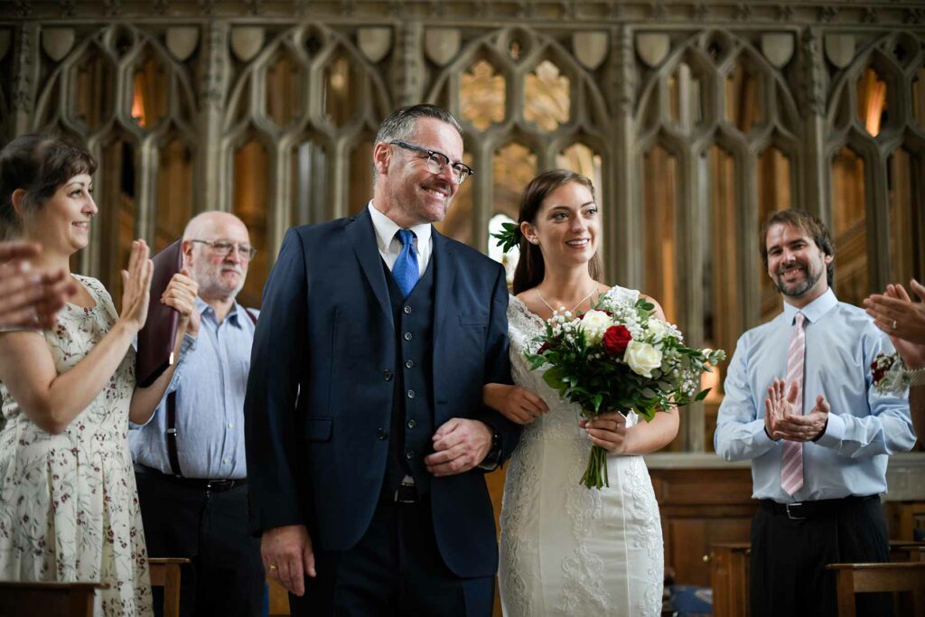 A bride is walked down the aisle with her father during a religious wedding ceremony processional