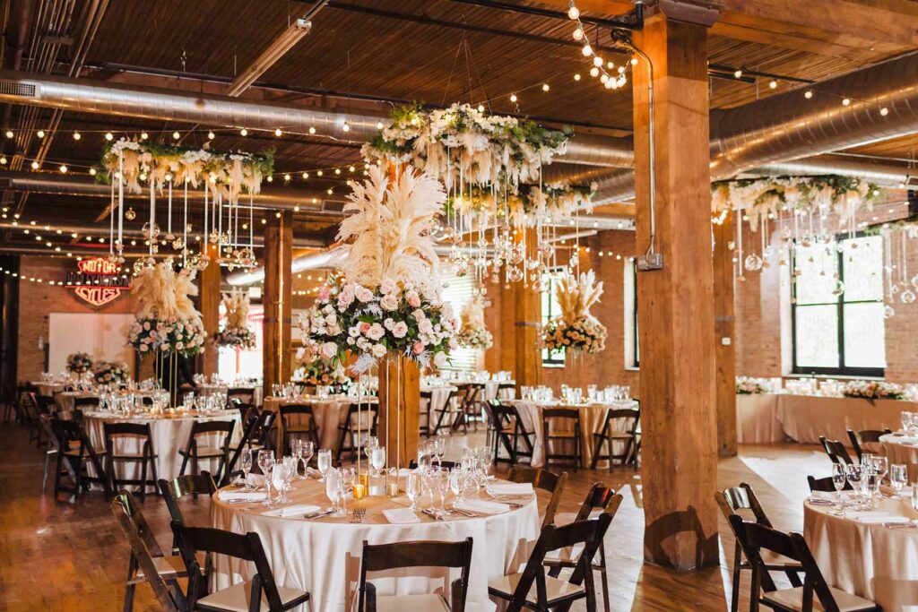 Lacuna loft wedding venue in Chicago with brick walls and exposed ceiling, decorated with hanging floral arrangements and tables set with wooden chairs