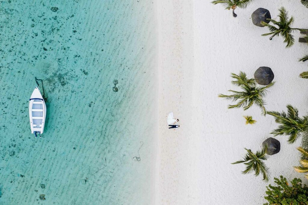 An aerial view of a couple in wedding attire lying on the shores of Mauritius