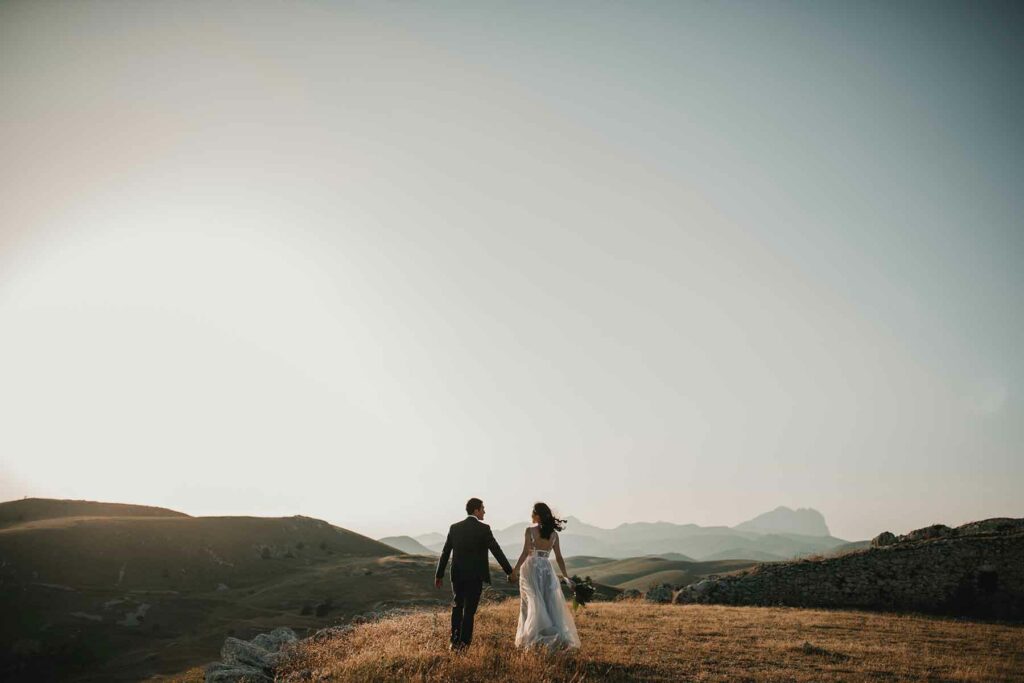 A couple holding hands looking out on hills during their destination wedding