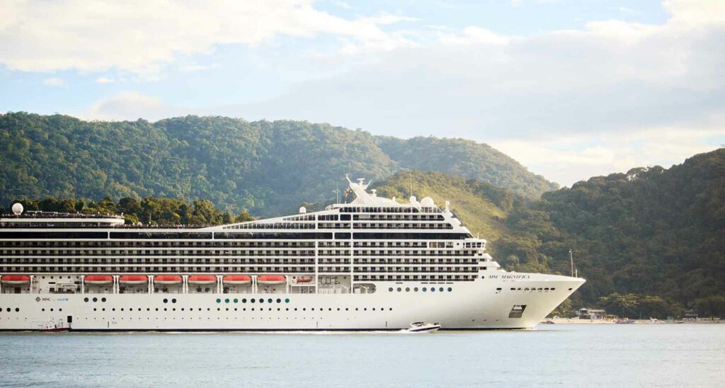 A large cruise ship with green hills in the background