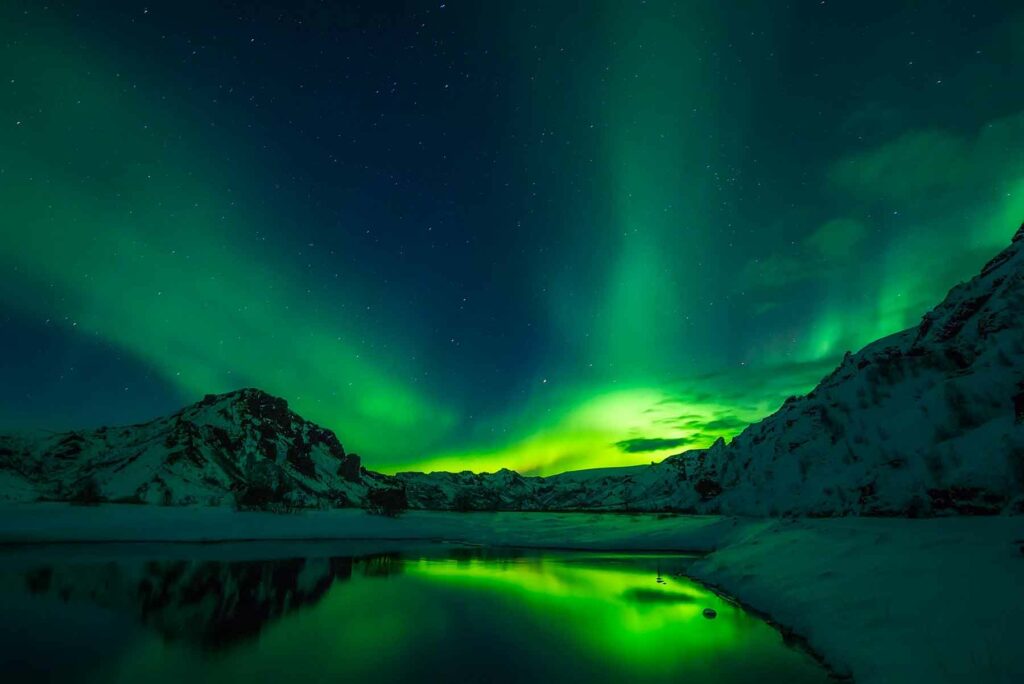 Northern Lights dancing behind a snow-capped mountain in Iceland