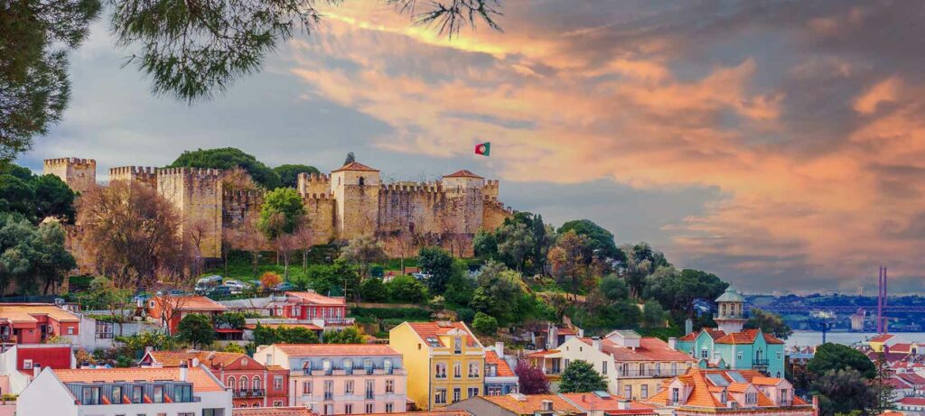 The St. George historical castle in Lisbon, surrounded by colorful houses at sunset