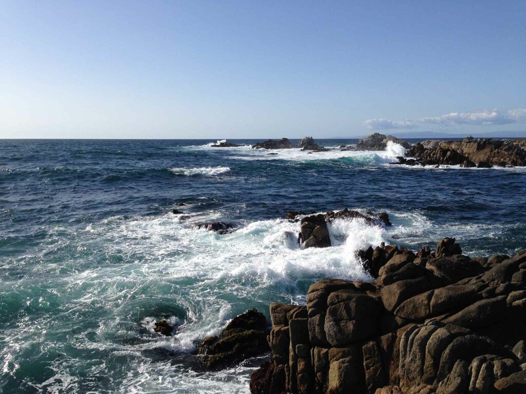 Waves crashing against a rocky shore in Monterey, California
