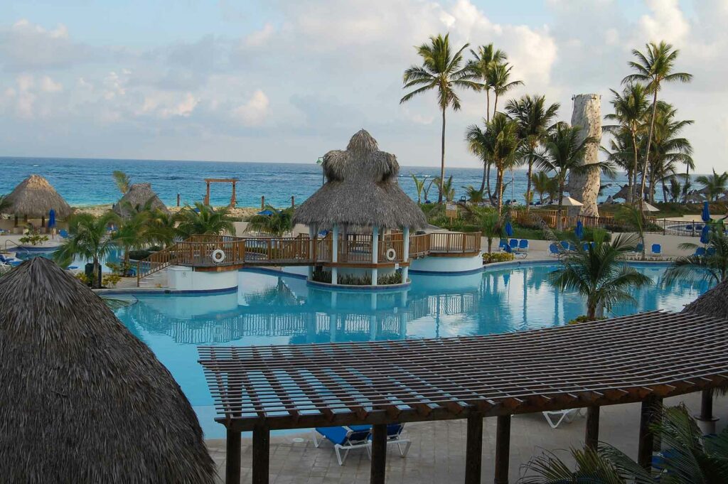 A view of palm trees, pools and a thatched roof at a resort in Punta Cana in the Dominican Republic
