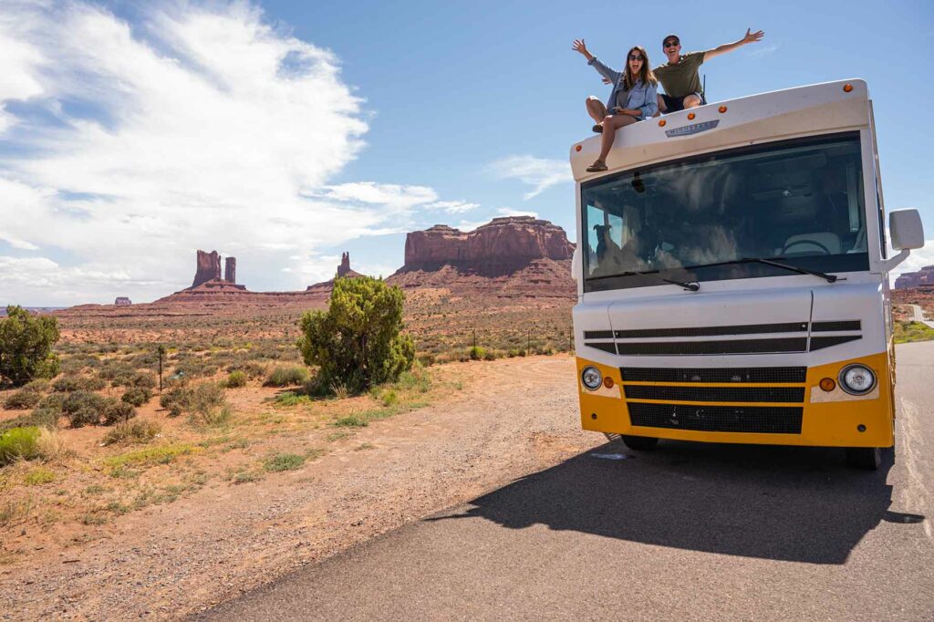 A couple sitting on an RV while on a honeymoon road trip in the desert