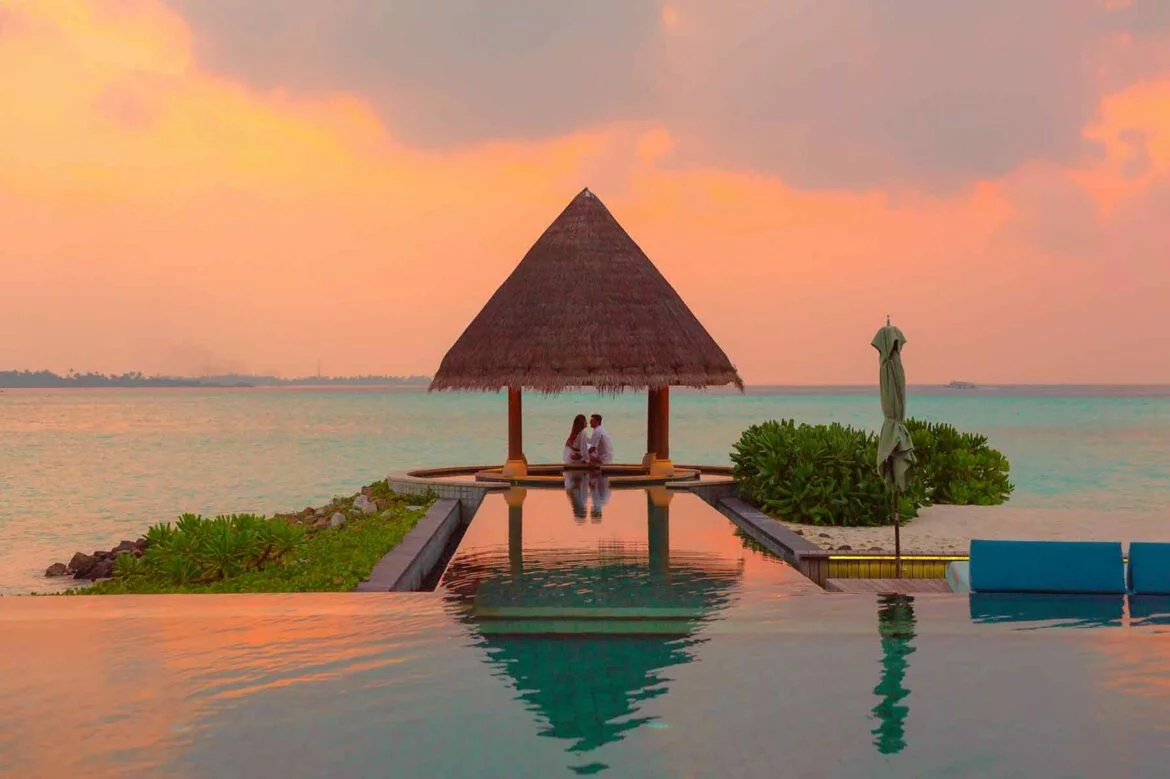 A couple on their honeymoon under an infinity pool hut looking out to sea