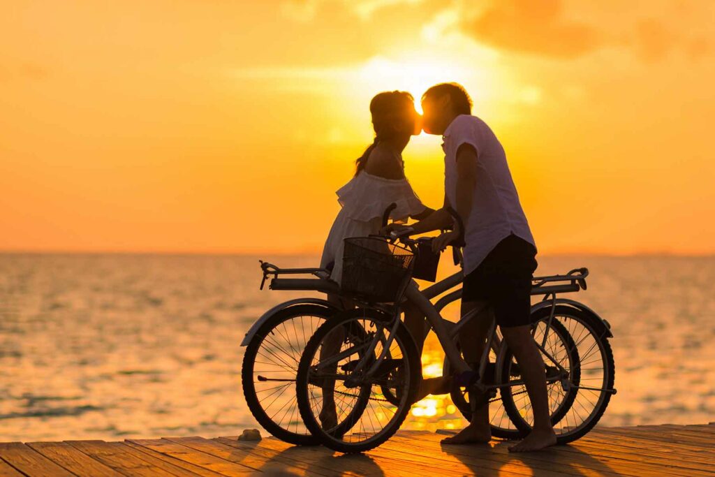 A man and woman kissing on their waterfront honeymoon at sunset