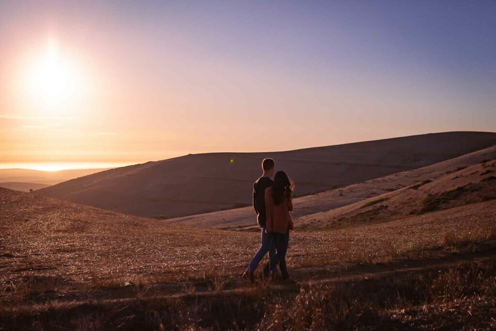 An outdoor proposal in the countryside with two couples walking at sunset on a hilly path