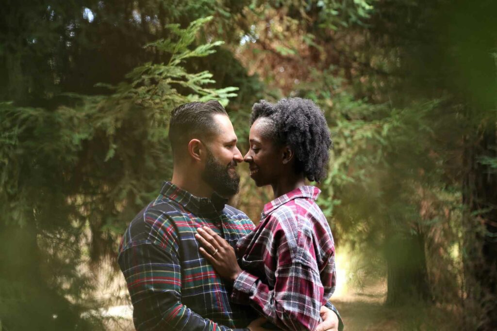 An outdoor proposal in a forest with two people embracing while surrounded by wooded trees