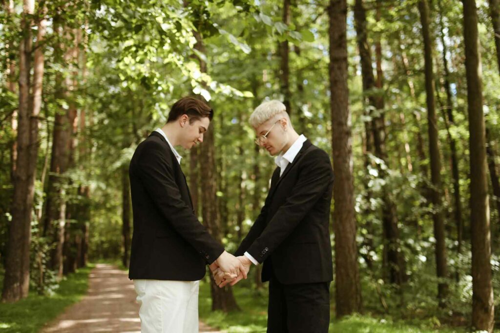 Two. men grasping hands in a forest during an outdoor proposal