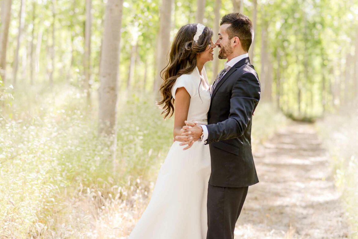 A couple embracing at their spring wedding in a light and airy outdoor venue surrounded by trees