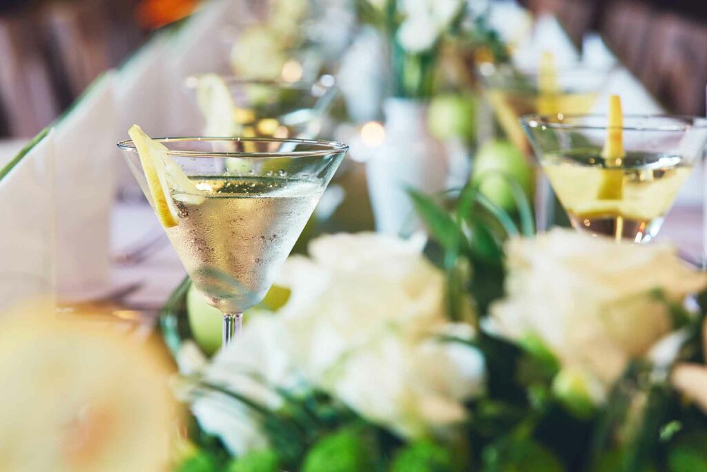 A close-up of a lemon drop spring cocktail nestled on a table filled with flowers and greenery