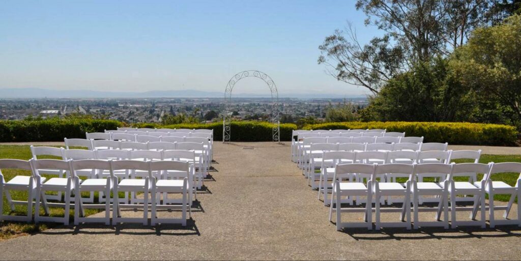 The outdoor space at the Oakland Zoo Snow Building set up for a wedding with chairs facing a view of the city