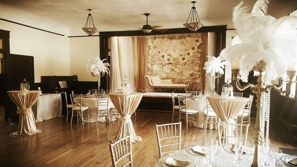 Interior of the San Jose Clubhouse decorated for an elegant wedding reception with tables, chairs and a stage with a chaise lounge
