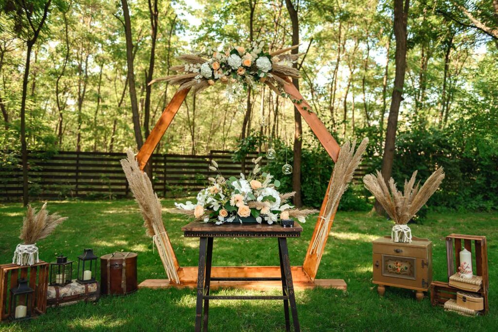 A fall wedding arch decorated with pampas grass and wooden accents such as tables and vintage crates