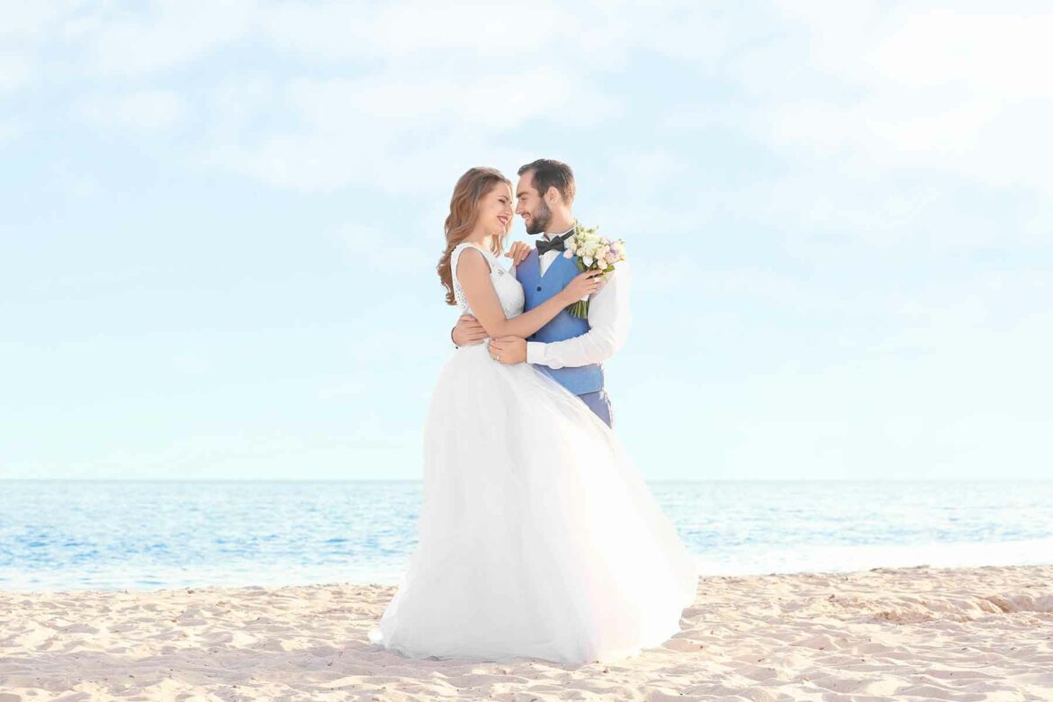A couple standing on the beach after their summer wedding
