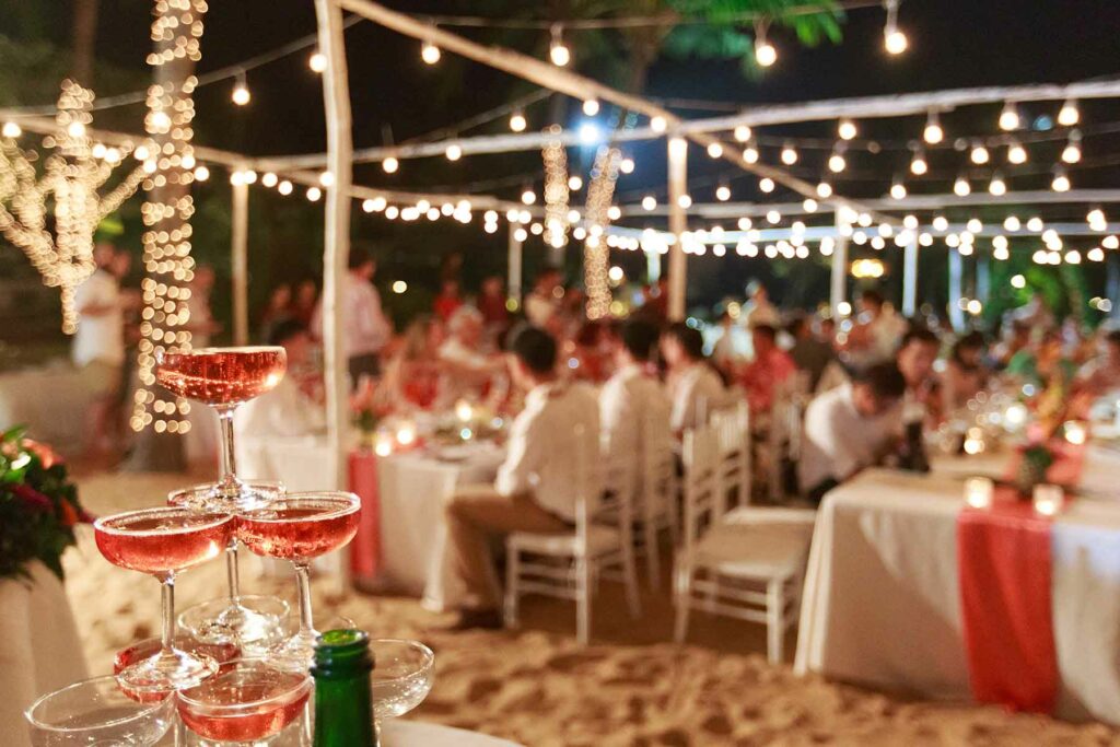 Summer wedding reception on the beach featuring twinkle lights over reception tables