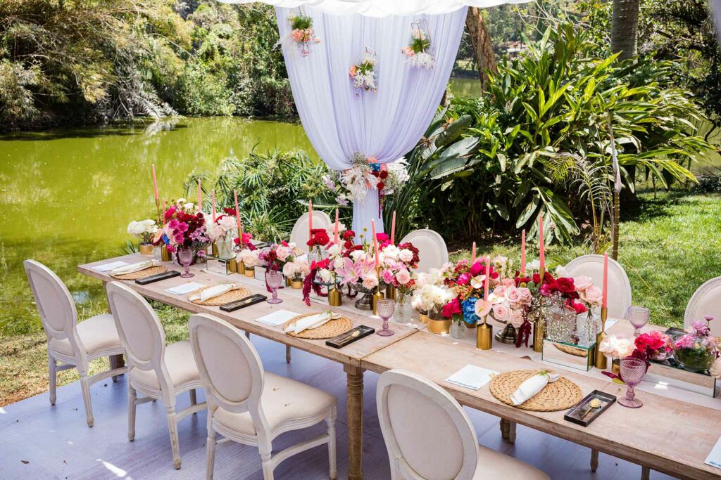 summer wedding venue next to a lake with a table set with pink flowers