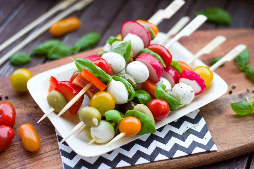 Summer wedding menu featuring fresh skewers of produce including tomatoes, radish and mozzarella cheese