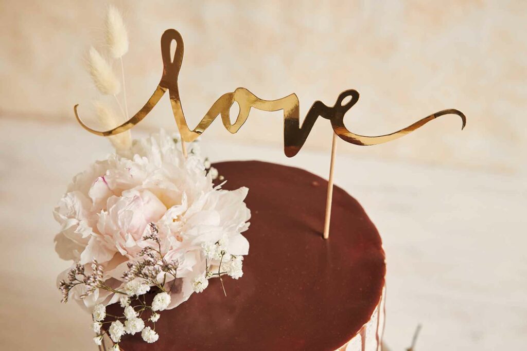 Custom cake topper that reads "love" in script in gold foil