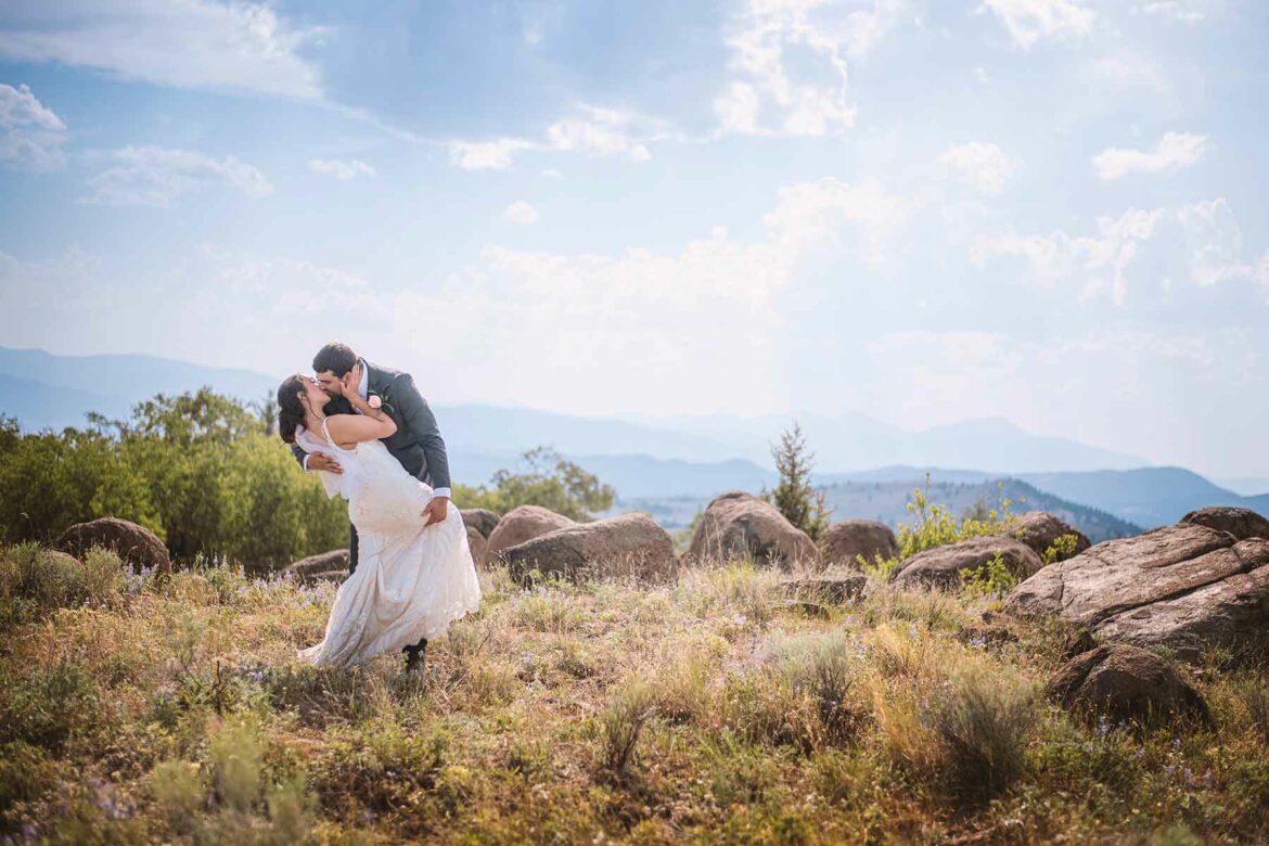 A couple in wedding attire embraces at the top of a mountain in Butte, Montana
