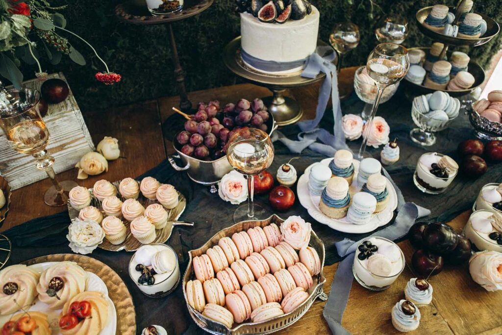 A micro wedding dessert bar featuring mini cupcakes on a gold leaf platter and macaroons