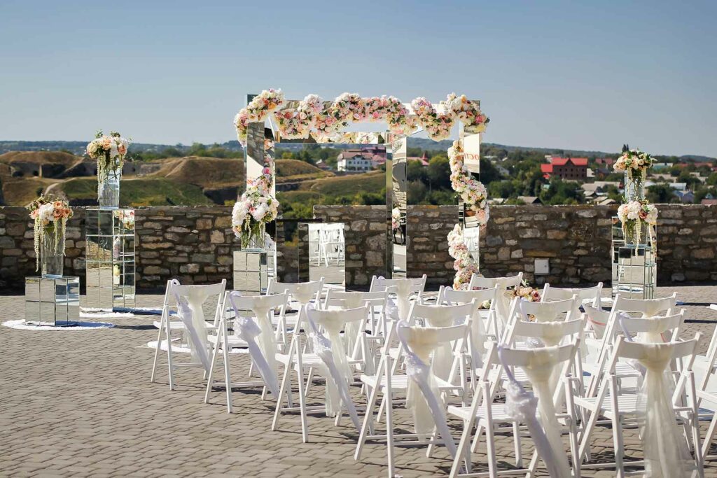 A beach micro wedding ceremony with 20 chairs set up behind a canopy wrapped in flowers