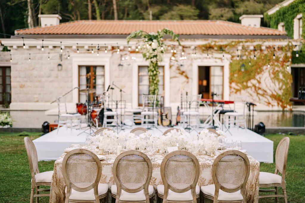 A backyard micro wedding with a reception table set for 10 and a small stage with wedding band equipment