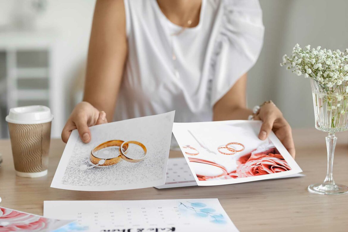 A woman creating a wedding vision board holding two photographs of wedding bands