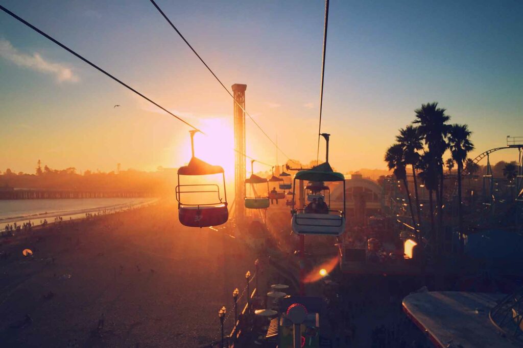 A couple riding the aerial tram ride along the Santa Cruz Boardwalk during sunset